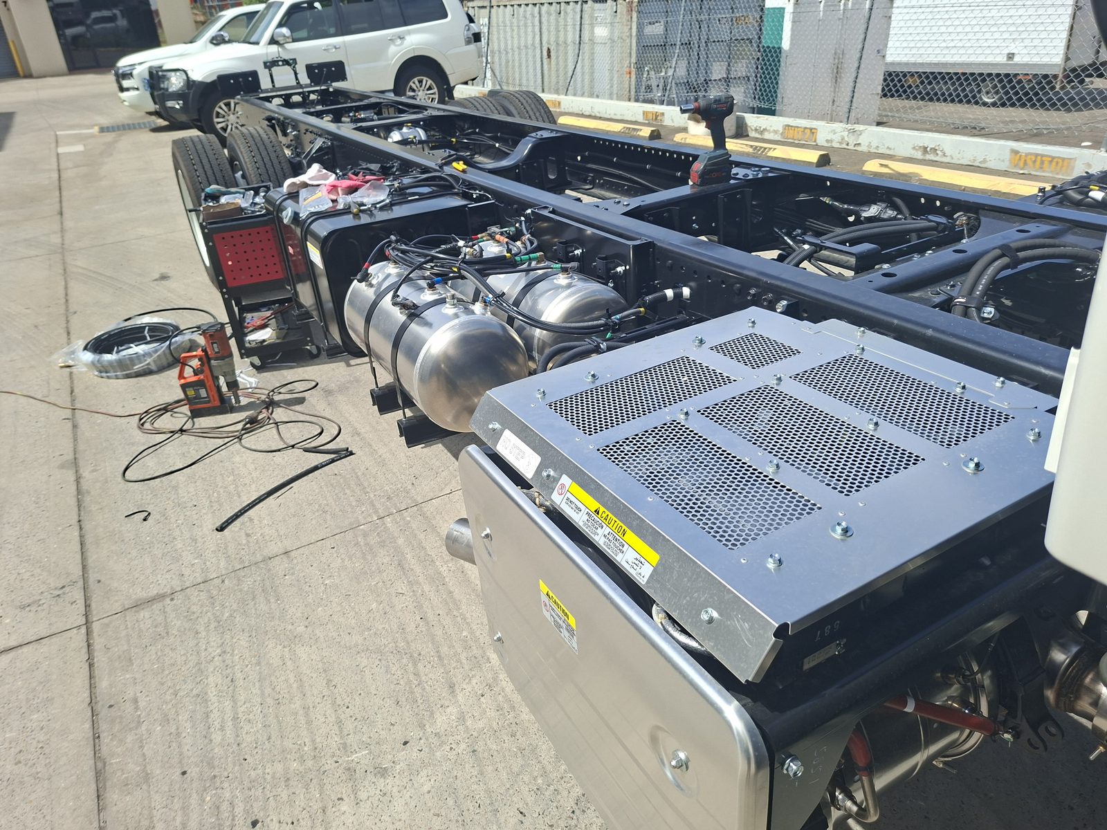A bare Isuzu cab-chassis outside the workshop