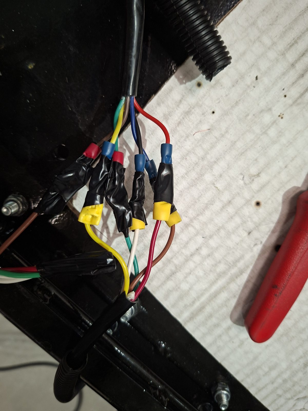 Colour-coded crimp connectors joining the wired controller to the hydraulic pump wiring on the truck frame