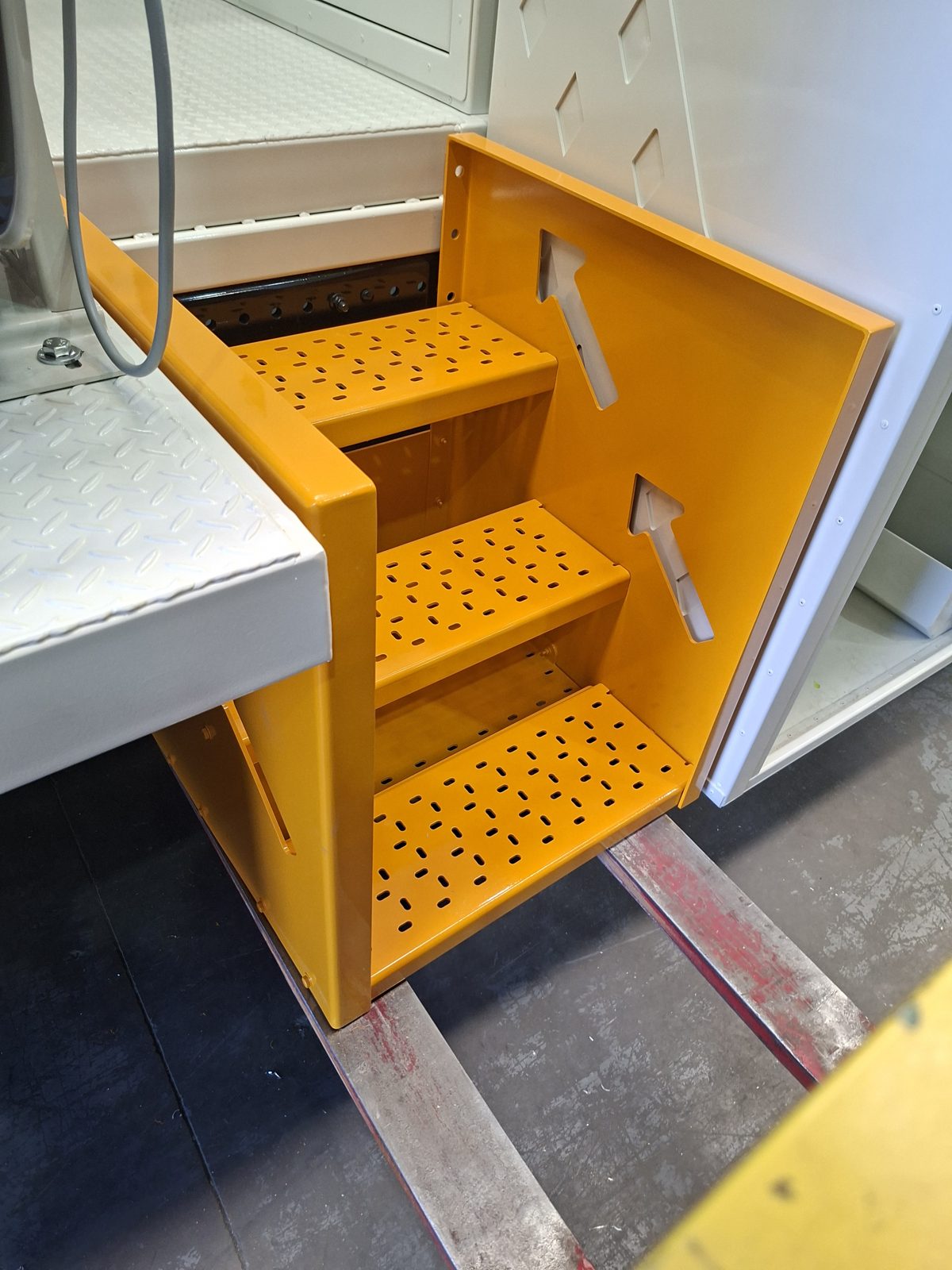 Orange aluminium stair assembly mounted on the side of a completed truck