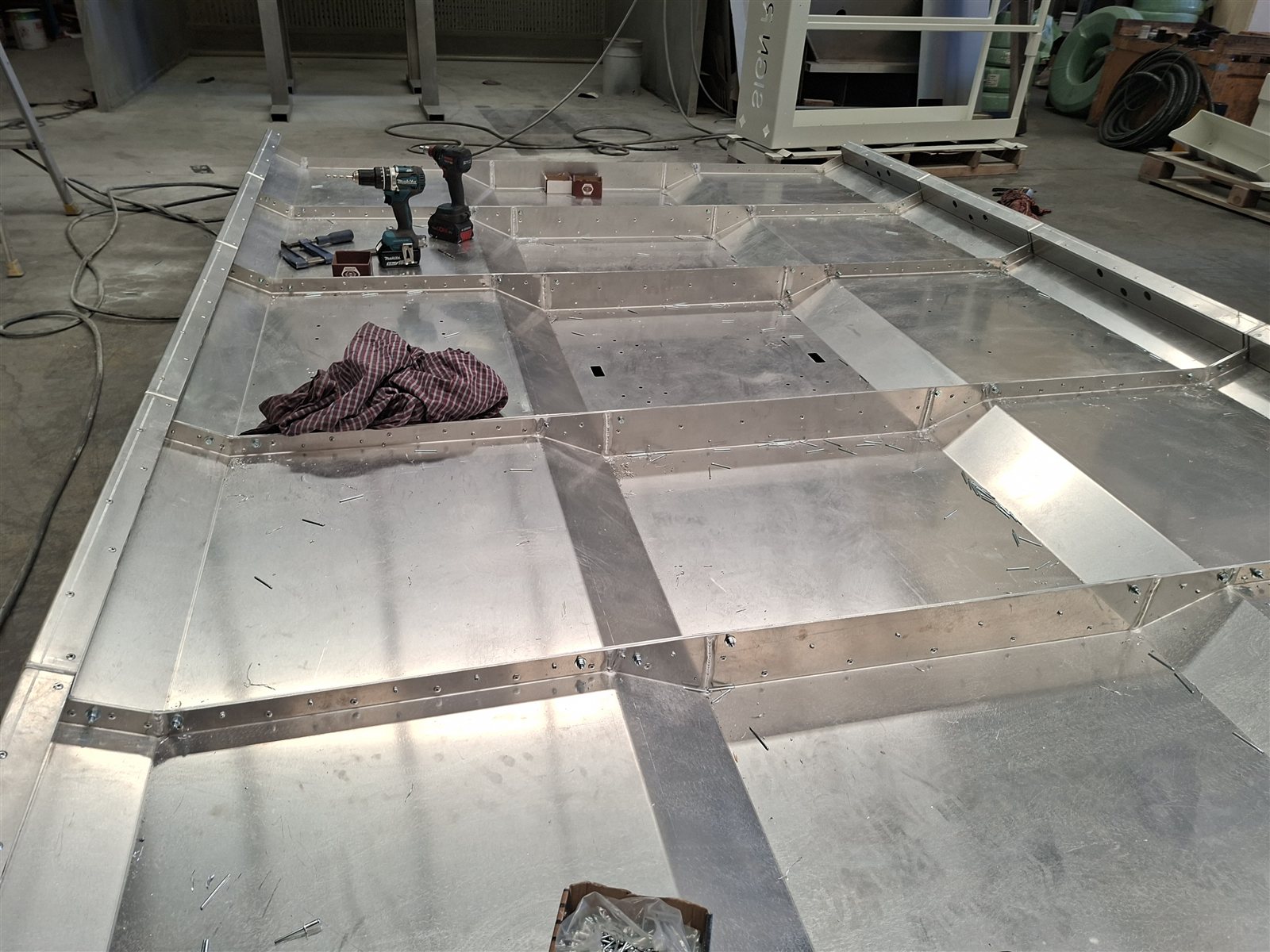 A large aluminium roof panel mid-assembly with tools resting on it