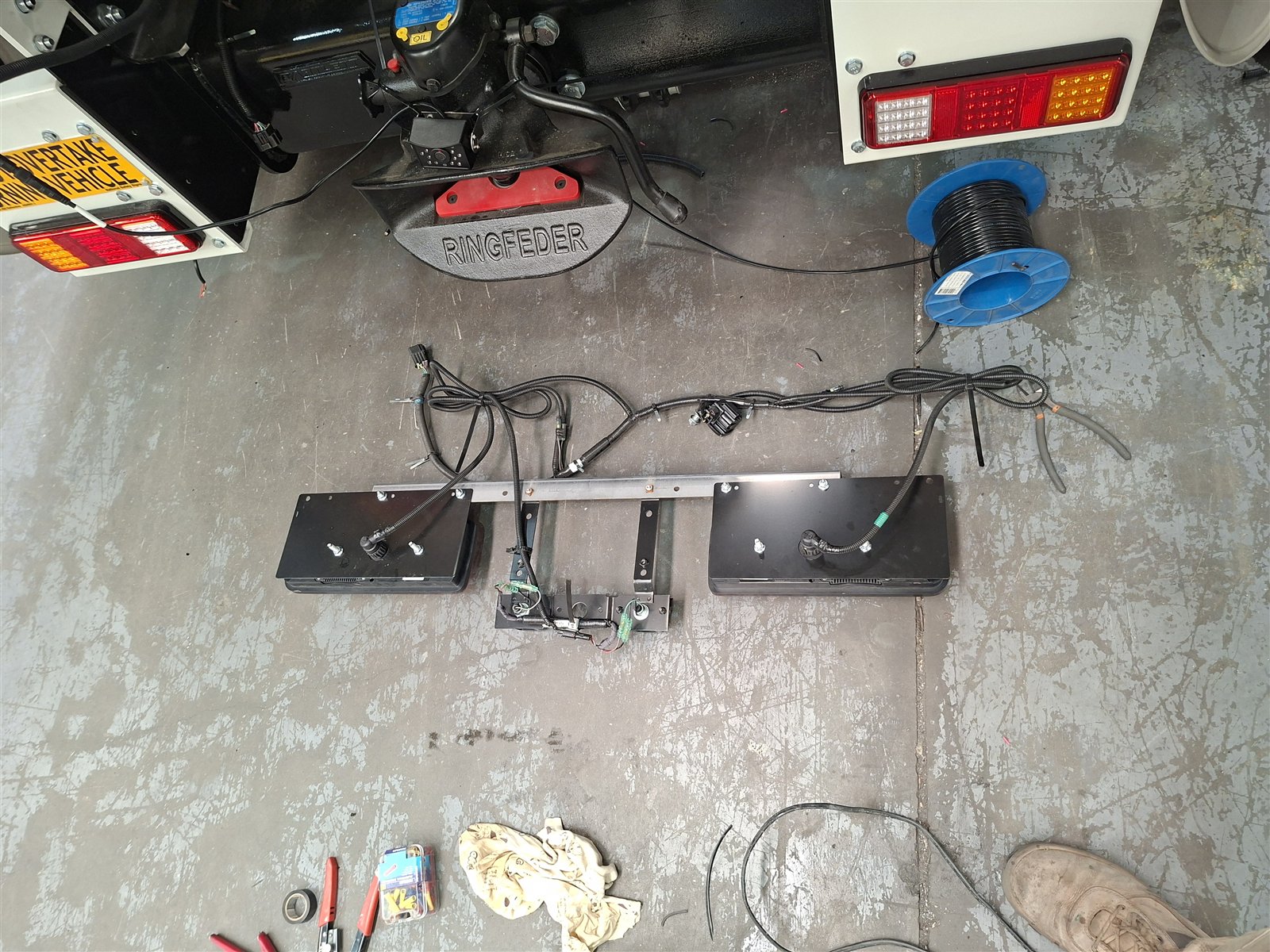 The original rear lighting harness and bumper, removed from the base chassis and laid out on the workshop floor